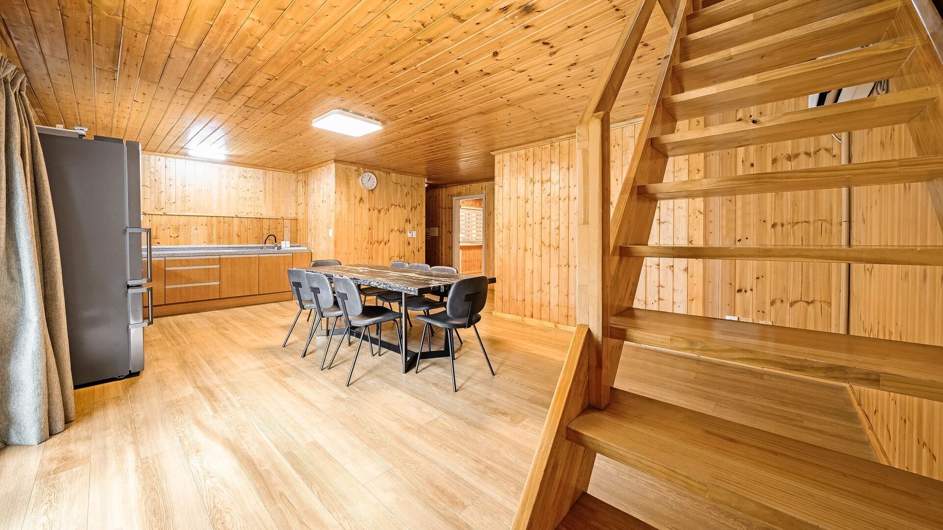 Un interior de madera con cocina, comedor y escalera.