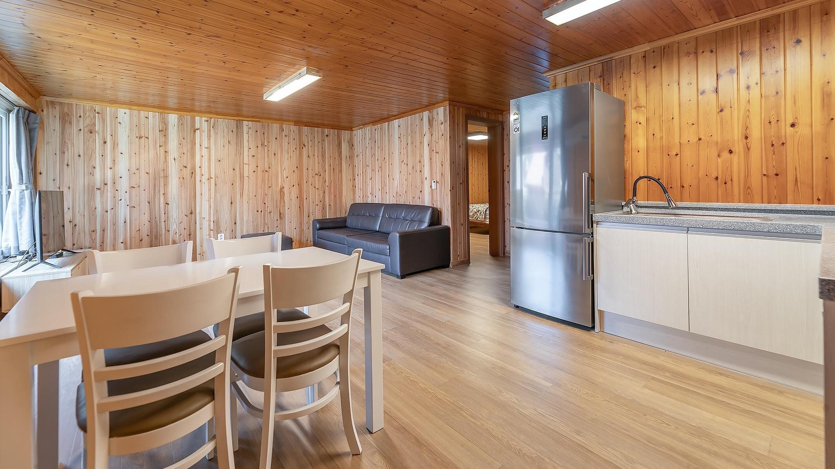 Un interior de madera con comedor, sofá y cocina.