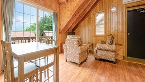 A cozy wooden cabin with a dining area, two patterned armchairs, and a black door.