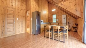 A spacious wooden interior with a kitchen area, including a refrigerator, microwave, and sink.