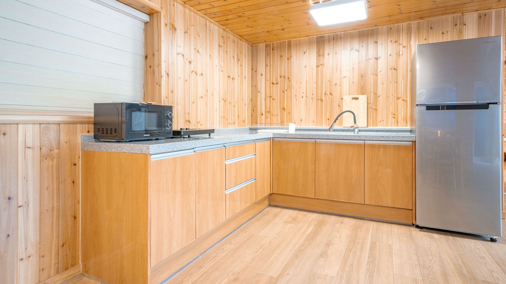 A kitchen with wooden cabinets, a microwave, a sink, and a refrigerator.