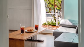 Un comedor con una mesa de madera, dos bebidas, un pastel y un sofá gris.
