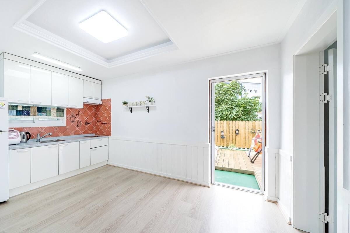 Eine moderne Küche mit weißen Schränken, einer Edelstahlspüle und Holzdielen.