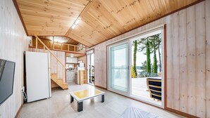Interior de madera con cocina, comedor y un balcón con vistas.