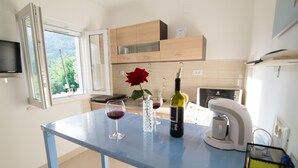 Une cuisine avec une table bleue, des verres à vin, une bouteille de vin et une rose.