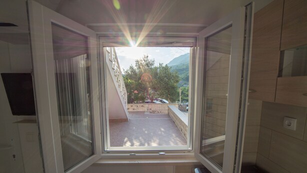 Une pièce dotée d’une grande fenêtre, donnant sur un balcon, et dont le sol est recouvert de carreaux.