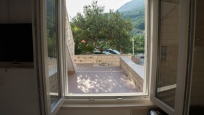 Une pièce dotée d’une grande fenêtre donnant sur une cour intérieure où se trouvent un arbre et une voiture.