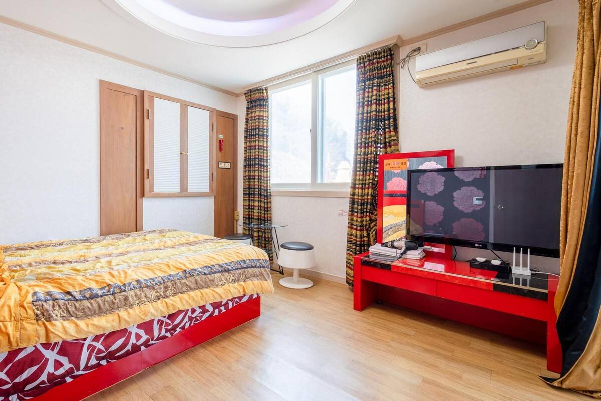 Une chambre à coucher avec un lit, une télévision, un bureau et une fenêtre.
