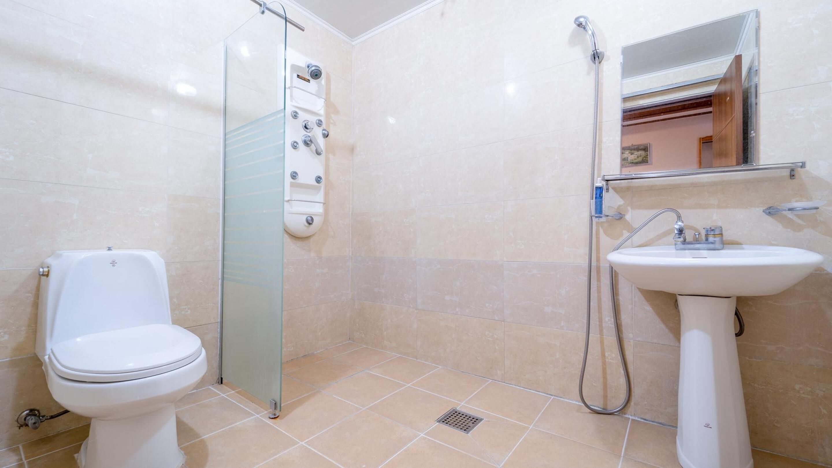 A bathroom with a toilet, a glass shower enclosure, and a sink with a mirror above it.