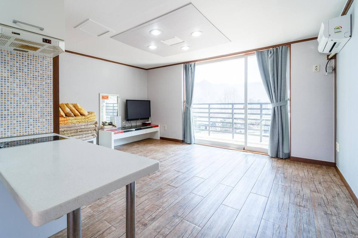 Une chambre d’hôtel avec un grand lit, une télévision, un bureau et un balcon avec des rideaux.