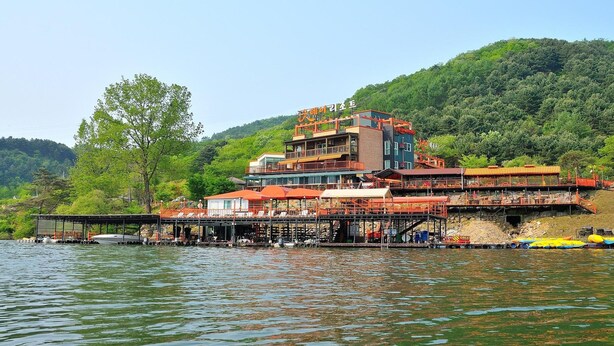 Un edificio a più piani sul lungomare con posti a sedere all'aperto e un molo che si protende nell'acqua.