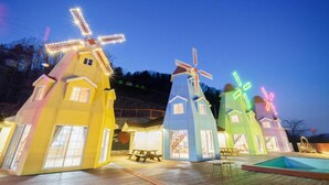 Una fila di mulini a vento colorati con le cime illuminate, un pontile di legno e un’area piscina.