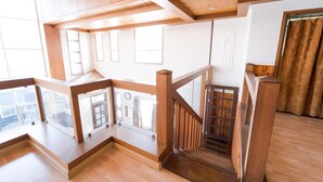 Una scala in legno con ringhiera in vetro che conduce a un balcone.
