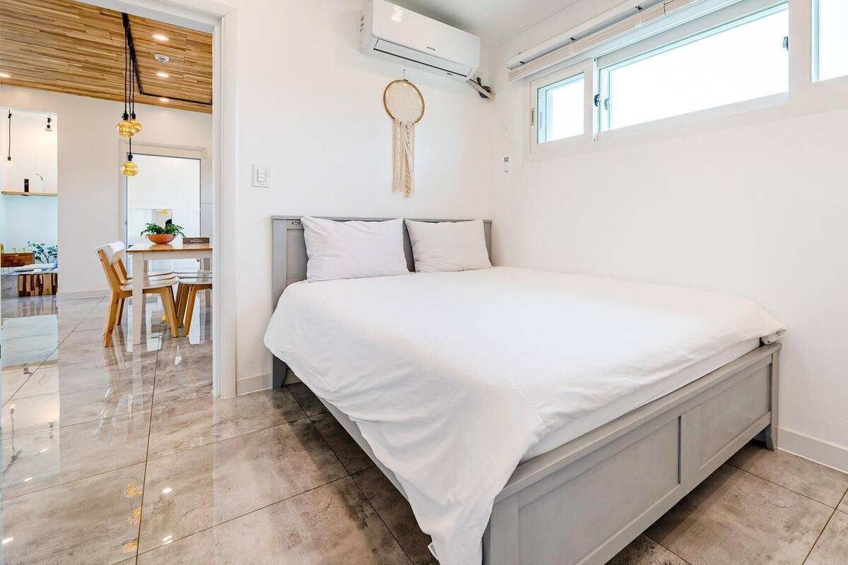 Et moderne soveværelse med seng, spiseplads med bord og stole, samt en aircondition.