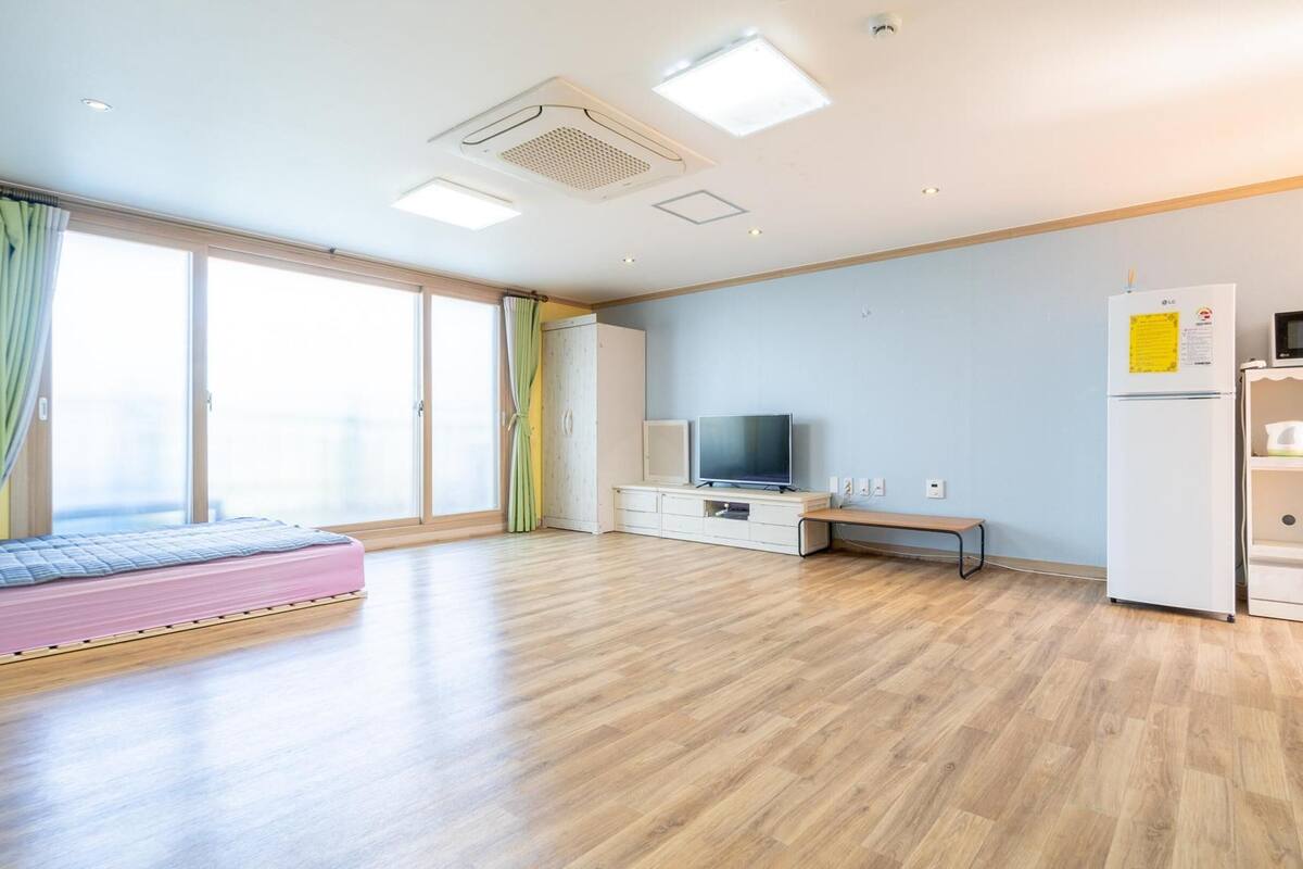 Moderni hotellihuone, jossa on sänky, televisio, mikroaaltouuni ja jääkaappi.