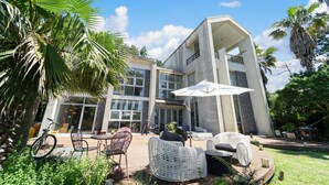A modern building with a patio area featuring wicker furniture and a white umbrella.