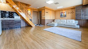 Ein modernes Wohnzimmer mit einer Holztreppe, einem weißen Sofa und einer Küchenzeile.