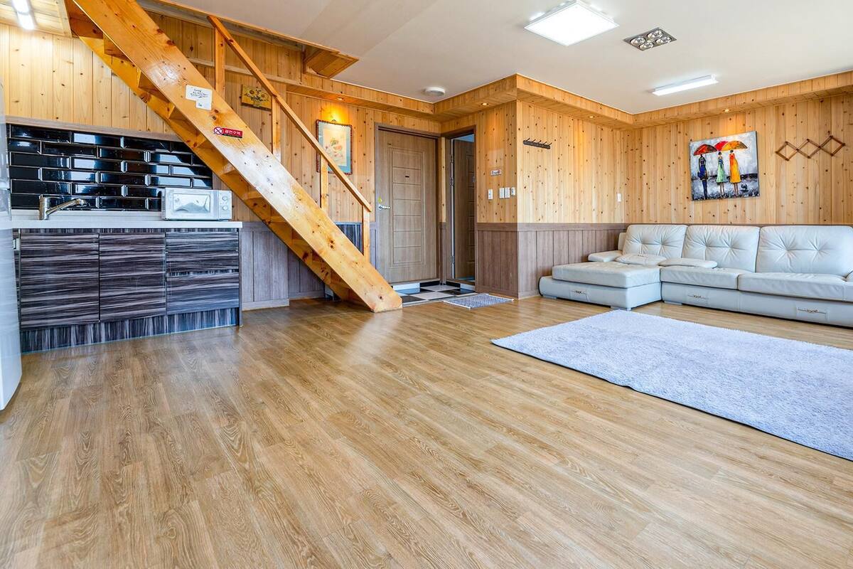 Ein modernes Wohnzimmer mit einer Holztreppe, einem weißen Sofa und einer Küchenzeile.