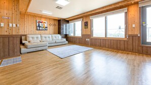 Ein geräumiges Wohnzimmer mit einer großen Couch, Holzwänden und bodengrossen Fenstern mit Blick.