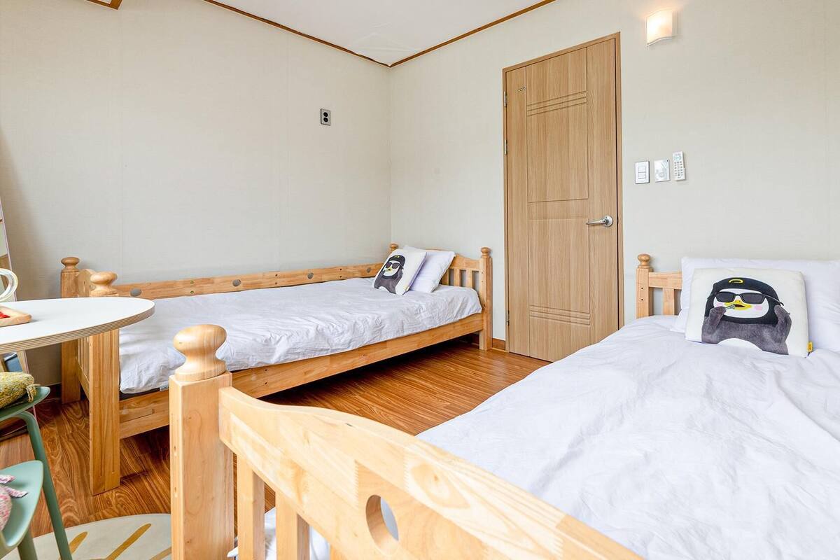 Une pièce avec deux lits en bois, une table ronde et une porte.