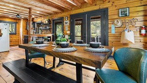 Un intérieur en bois avec une table à manger dressée pour quatre personnes, un banc et une chaise.