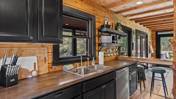 Une cuisine avec des meubles de rangement en bois, un évier en acier inoxydable et un plan de travail en bois.