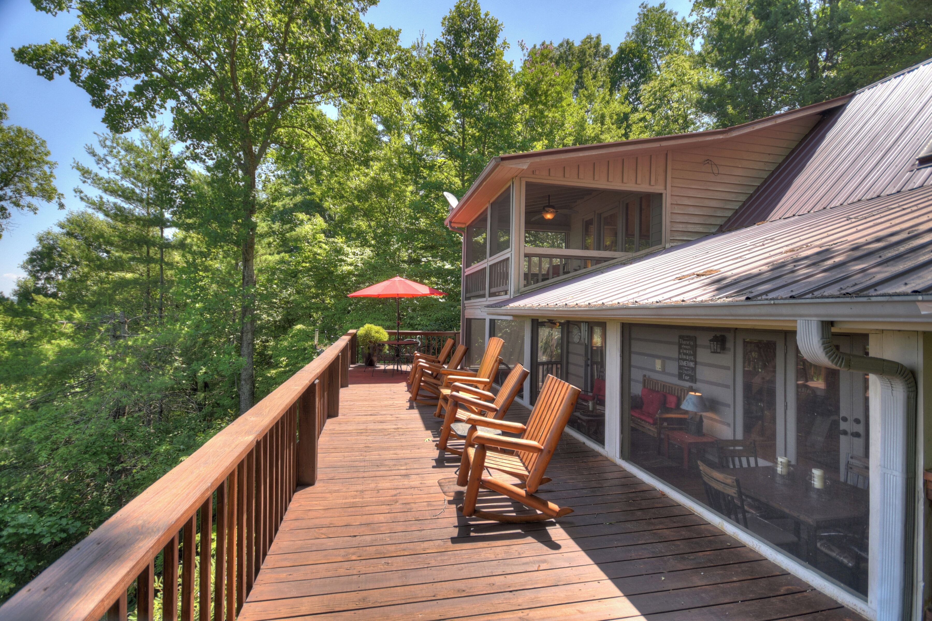 A wooden deck with outdoor seating and a view of a building with a sloped roof.