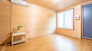 Una habitación con paredes de madera y un ventanal grande. Hay una mesa pequeña con una planta encima.