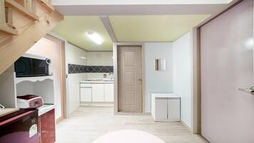 Una cocina compacta con armarios blancos, una puerta de madera y una pequeña encimera.