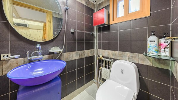 Un baño con un lavabo azul, un inodoro blanco, una ducha y un espejo.