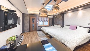 Un dormitorio moderno con una cama grande, un televisor montado en la pared y un escritorio con una computadora.