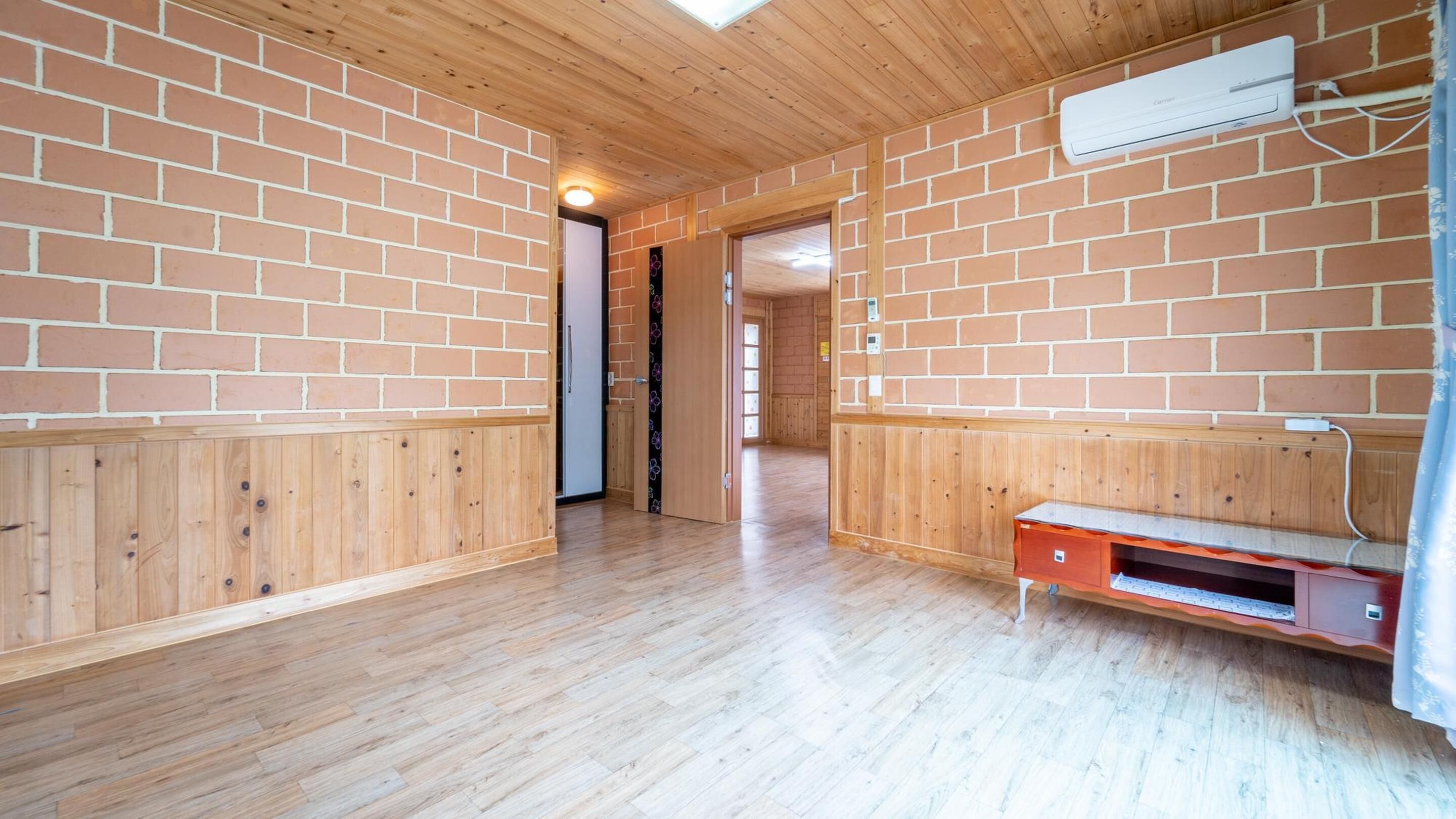 Una habitación con paredes y pisos de madera, un banco integrado y un equipo de aire acondicionado.