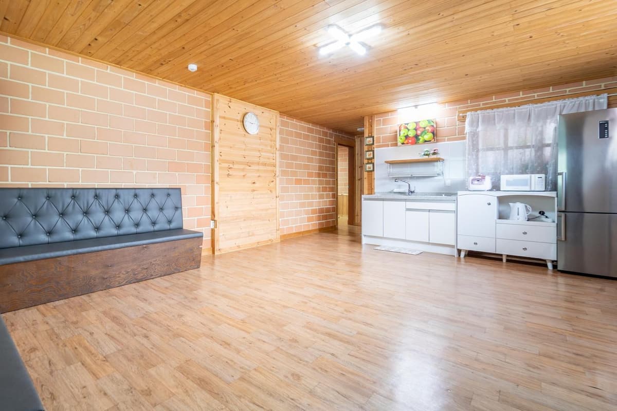 A modern kitchen with a brick wall, wooden ceiling, and a built-in bench.