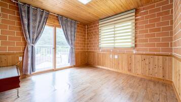 A room with wooden flooring, a sliding glass door, and a window with blinds.
