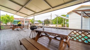 A covered outdoor deck with picnic tables and a grill. - Samcheok Dasarang Pension (Samcheok)
