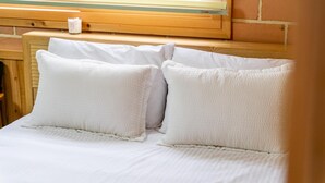 A bed with white linens and pillows, a wooden headboard, and a small bedside table with a candle. - Samcheok Dasarang Pension (Samcheok)