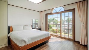 A bedroom with a large bed, a nightstand, a mirror, and a sliding glass door leading to an outdoor area. - Jeju Sigan Yeohaeng Huyang Pension (Jeju City)