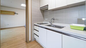 A modern kitchen with white cabinets, a stainless steel sink, and a light-colored countertop. - Seogwipo Narsha Resort (Seogwipo)