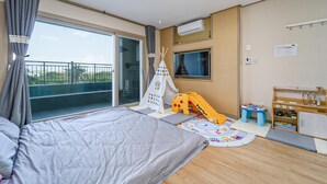 A bedroom with a bed, a play area with a slide, a TV, and a kitchenette. - Seogwipo Narsha Resort (Seogwipo)