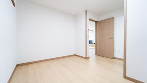 A room with a wooden floor, white walls, and a wooden door.