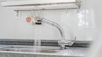 Uma pia de cozinha moderna com uma torneira cromada, bancada de granito e painel de azulejos branco.
