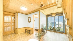Una habitació àmplia amb terres de fusta, una gran porta corredissa de vidre que dona a un balcó i una taula petita amb un ram de flors.