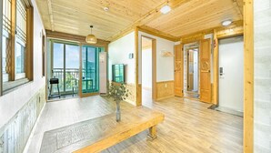Habitació àmplia amb terres de fusta, una banca, un gran finestral i una porta corredissa de vidre que dona a zona exterior.