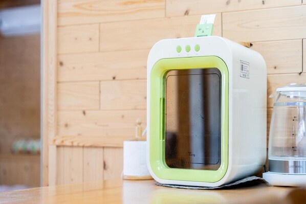 A portable microwave with a green and white design, placed on a wooden surface with a glass container nearby.