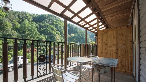 A wooden deck with a pergola, a table, and two chairs. - Gapyeong Supsokui Harmony Pension (Gapyeong)