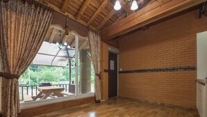 A spacious room with wooden flooring, a balcony with a wooden table, and a view of greenery outside. - Gapyeong Supsokui Harmony Pension (Gapyeong)