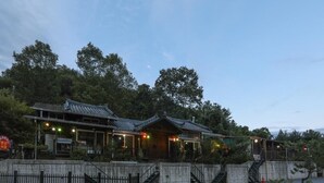 A traditional Japanese-style building with multiple levels and a sloped roof, surrounded by a fence and trees. - Gapyeong Supsokui Harmony Pension (Gapyeong)