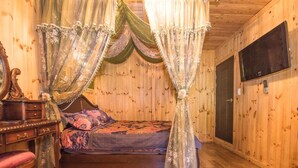 A room with a wooden floor, a bed with floral bedding, a nightstand, a mirror, and a wooden wardrobe. - Gapyeong Supsokui Harmony Pension (Gapyeong)