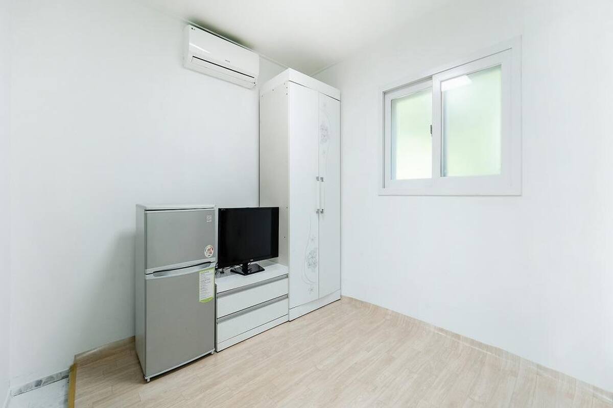 Une chambre dotée d’un réfrigérateur intégré, d’un téléviseur à écran plat, d’une armoire et d’une fenêtre.