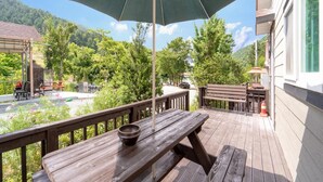 A wooden deck with a picnic table and umbrella, overlooking a garden and a mountain. - Hongcheon Daebakine Pension (Hongcheon)